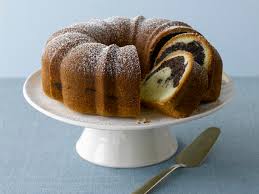 A marble bundt cake on a white cake stand with a knife beside it.