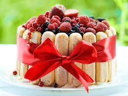 Elegant ladyfinger cake topped with fresh berries and tied with a red ribbon.