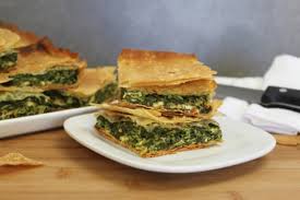 A stack of savory spinach and cheese pie slices on a white plate.