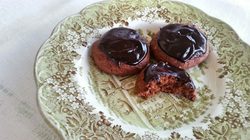 Chocolate-glazed cookies on a decorative plate, one partially eaten.