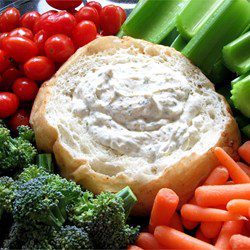 A vegetable platter with a bread bowl filled with creamy dip.