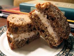 Two homemade chocolate chip cookie ice cream sandwiches on a plate.