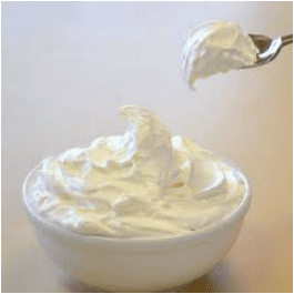 A bowl filled with creamy whipped topping and a spoon lifting some of it.