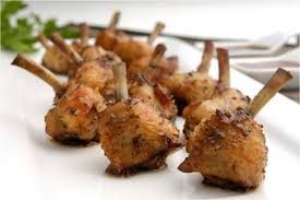 Close-up of grilled chicken drumettes on skewers.