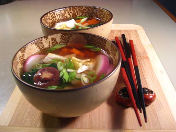 A bowl of Asian-style soup with chopsticks on a wooden board.