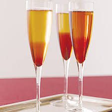 Three champagne flutes filled with amber-colored drink on a tray.