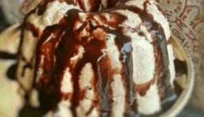 Close-up of creamy dessert drizzled with rich chocolate sauce.