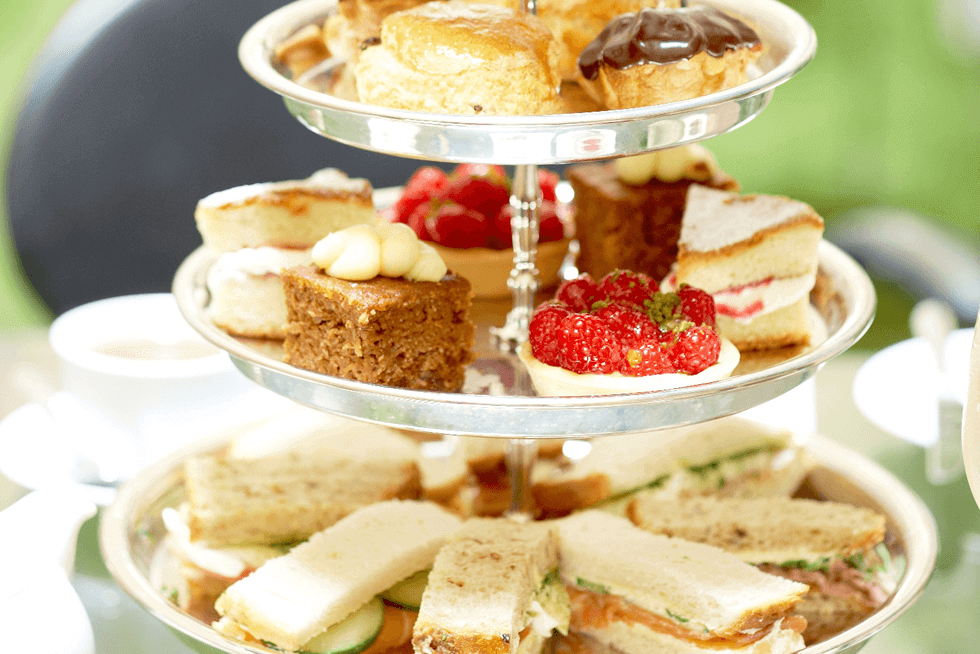 A tiered platter filled with assorted tea sandwiches and desserts.