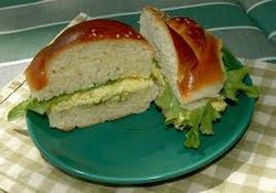 Two sandwich halves with egg salad on a green plate.