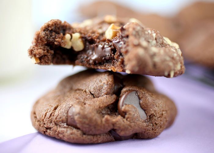 Two chocolate cookies stacked, one broken showing gooey chocolate inside.