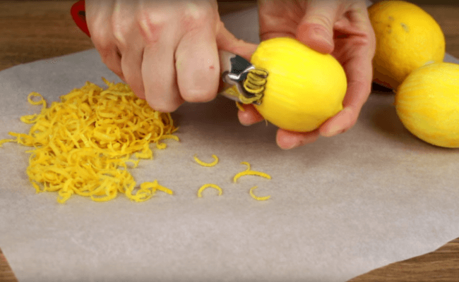 Hand grating a lemon zest over a surface.