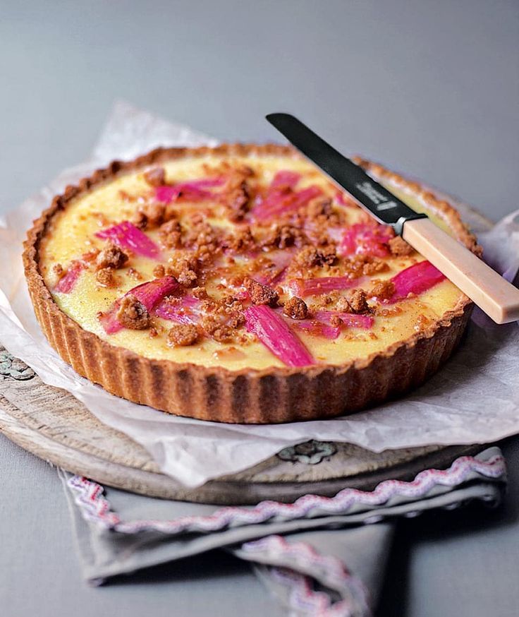 A creamy tart topped with pink petals and crumbled nuts.