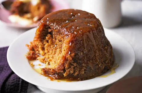 Sticky toffee pudding with caramel sauce on a white plate.