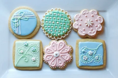 Decorative pastel cookies with intricate icing designs in blue, pink, and green.