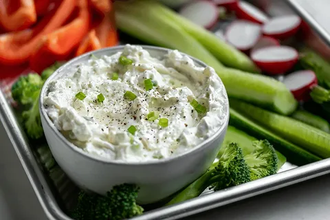 Creamy herb and onion dip in a white bowl.