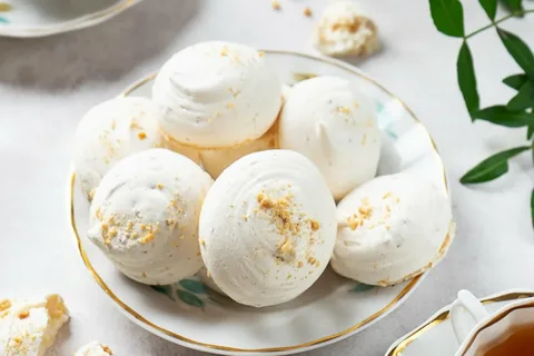 A plate of white meringue cookies with a crumbly topping.
