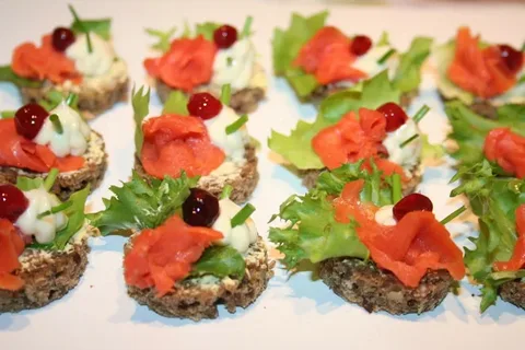 Open-faced sandwiches with lettuce, smoked salmon, and olives on bread.