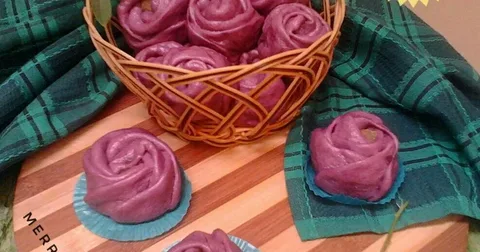A basket filled with purple rose-shaped sweets on a wooden table.