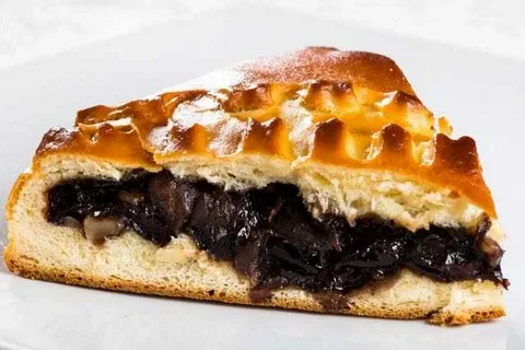 Close-up of a pie slice with dark filling and golden crust.