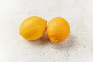 Two fresh lemons on a light surface.