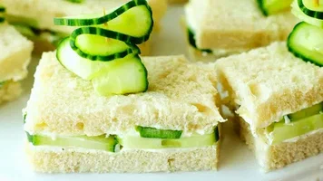Close-up of cucumber sandwiches with crusts removed on a white plate.