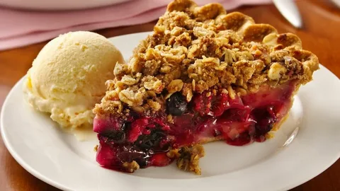 Slice of cherry crumble pie with vanilla ice cream.