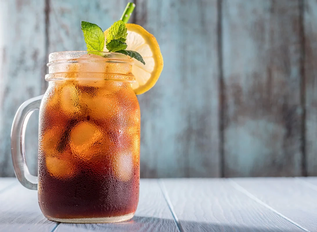 Iced tea in a mason jar with lemon and mint garnish.