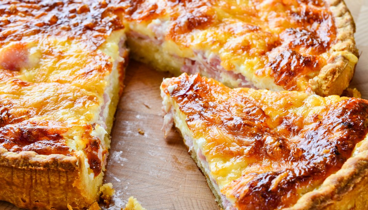A cheesy, golden-brown baked pie with a slice removed.