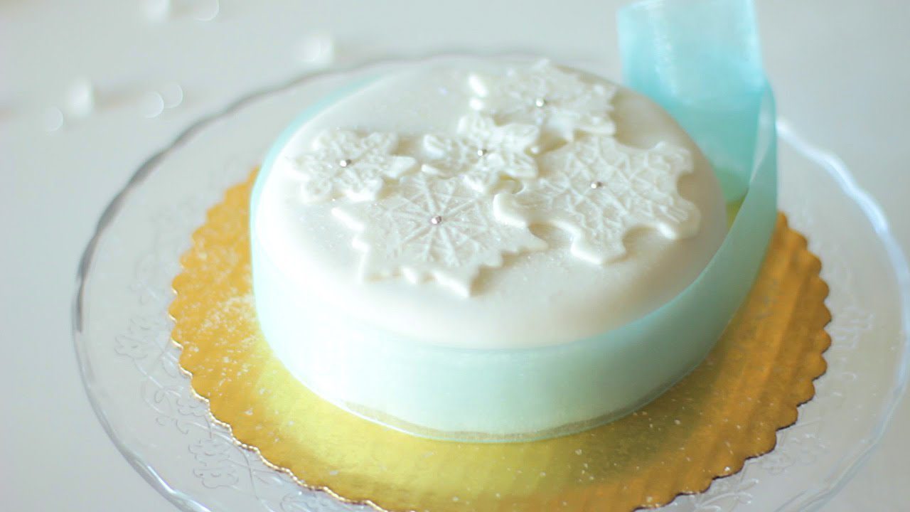 Elegant white cake with delicate snowflake decorations on top.