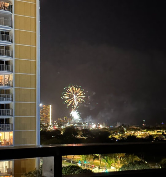 Fireworks lighting up the night sky near city buildings.