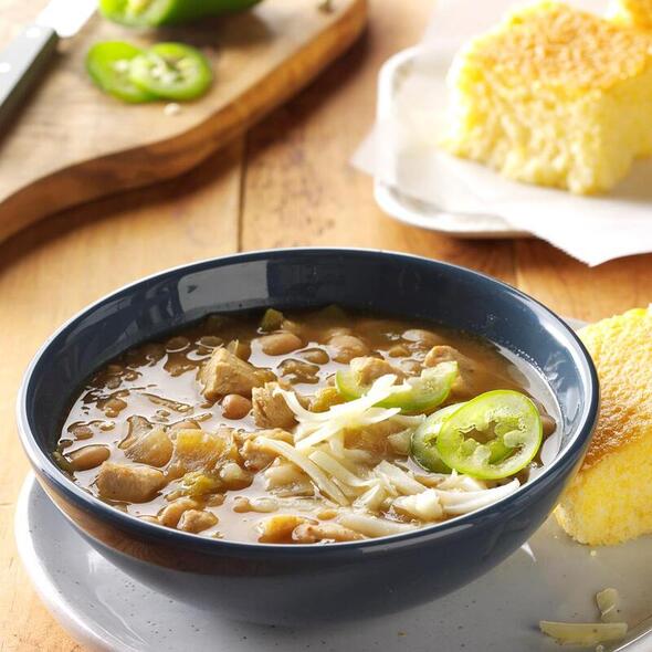 A bowl of hearty soup garnished with jalapeños and onions.