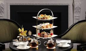 Elegant three-tiered stand with assorted pastries and tea cups on a table.