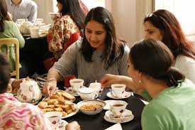 People enjoying tea and desserts together in a cozy setting.