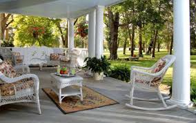 Cozy white porch furniture with greenery and trees in the background.