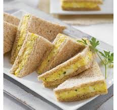 Triangular sandwiches with a yellow filling on a plate.