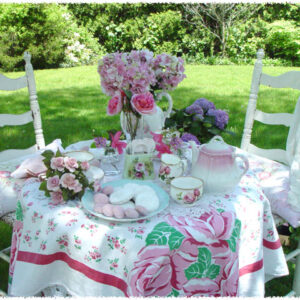 Charming outdoor tea party setup with floral decor and pink roses.