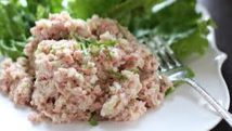 Close-up of creamy tuna salad garnished with herbs on a white plate.
