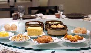 A table with dim sum dishes and drinks in a restaurant.
