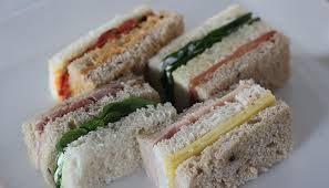 Assorted layered sandwiches with various fillings on white bread.