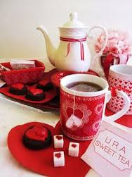 Red and white tea set with heart motifs and chocolates.