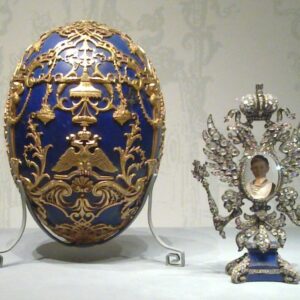 A richly decorated blue and gold Fabergé egg with a jeweled figurine.