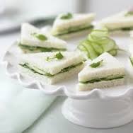 Elegant cucumber tea sandwiches on a white cake stand.