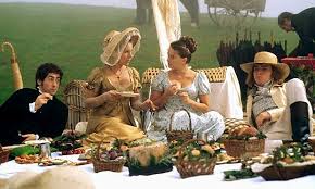 Two women in vintage dresses enjoying a picnic outdoors.