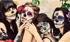 Four people with colorful Day of the Dead face paint posing together.