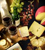 Wine glasses, cheese, and grapes on a wooden table for a cozy gathering.