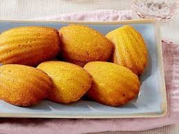 Golden madeleine cookies arranged on a white plate.