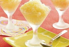 A frosty yellow shaved ice dessert in a scoop glass.