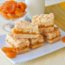 Delicious layered apricot dessert bars with crumb topping on a white plate.
