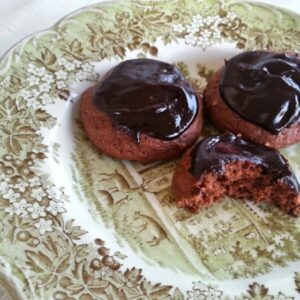 Chocolate-covered cookies on a decorative plate, one with a bite taken.