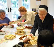 Group of elderly women enjoying tea and snacks together.